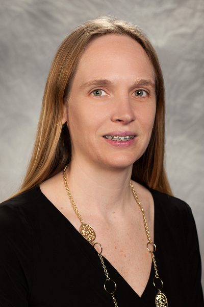 portrait photo of Denise Williams, a woman with braces and light brown hair, wearing a black shirt and long gold necklace