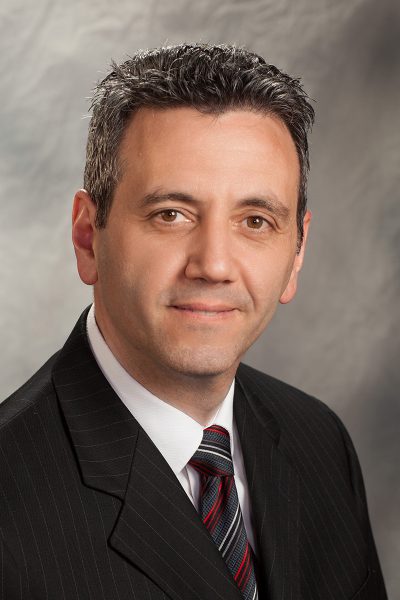 portrait photo of Dino Rosati, a man wearing a black suit jacket, and red, white, black, and gray striped tie