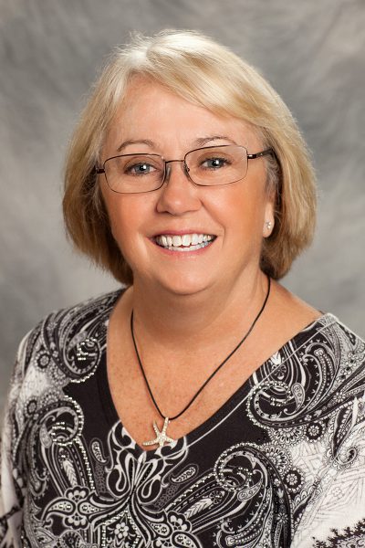 portrait photo of Margaret Foote, a woman with glasses wearing a star-shaped necklace and a gray patterned shirt