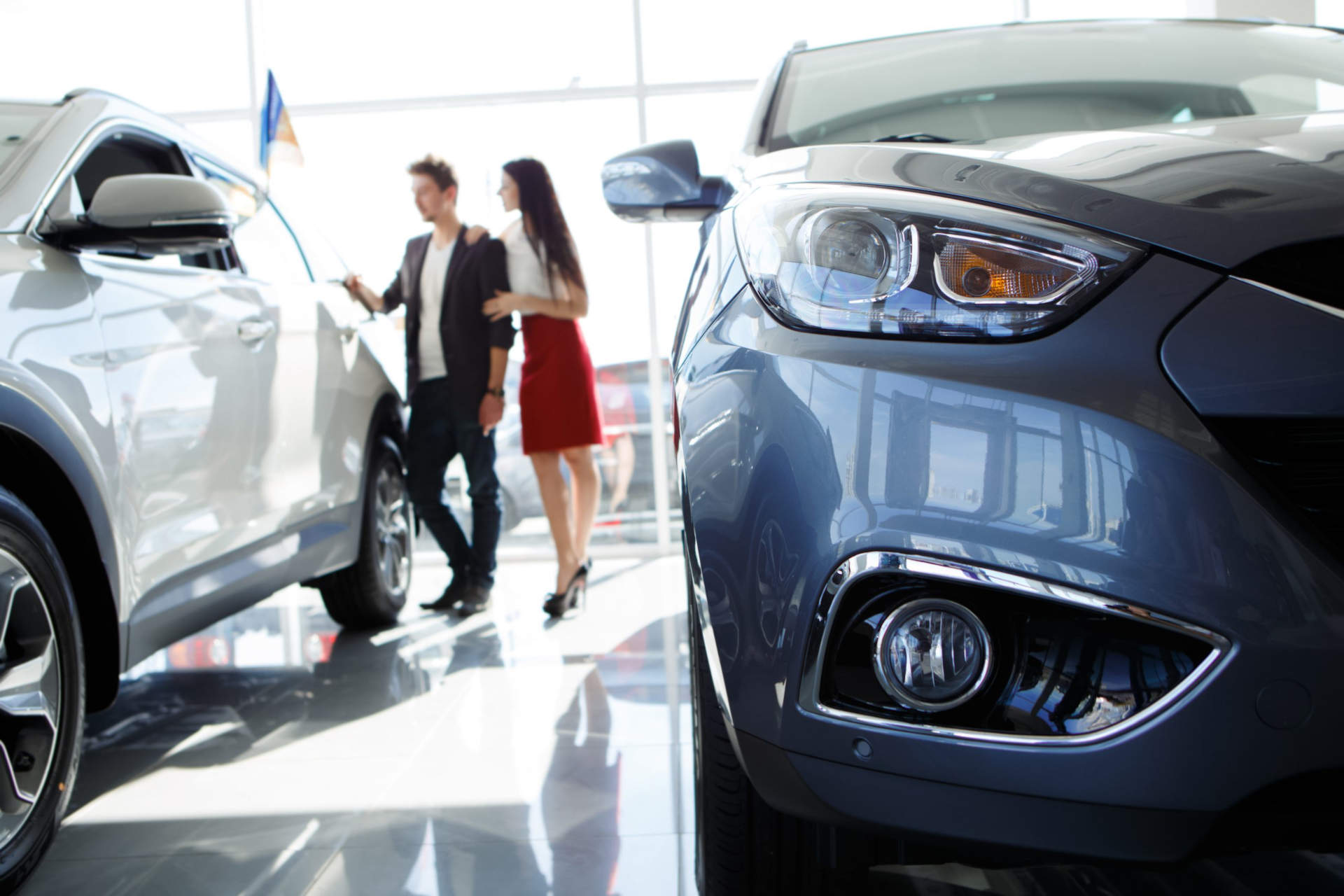 young couple looking at new cars at a dealership, avoiding these common car loan mistakes before they buy