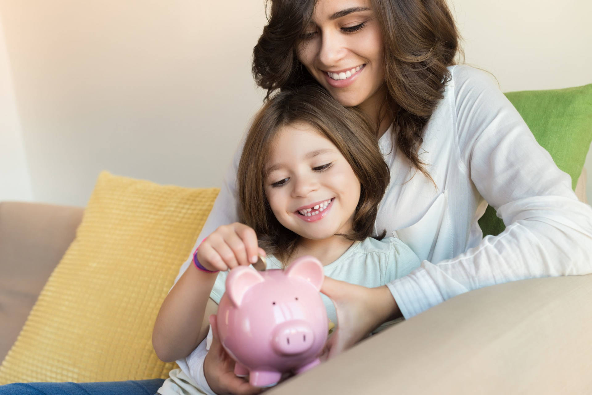 mother and young daughter start saving using a piggy bank, representing the benefits of setting up a youth savings account