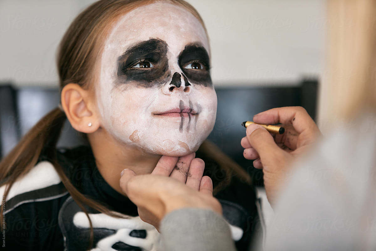 child getting skeleton makeup applied by parent who saved money on this Halloween costume idea by following helpful tips