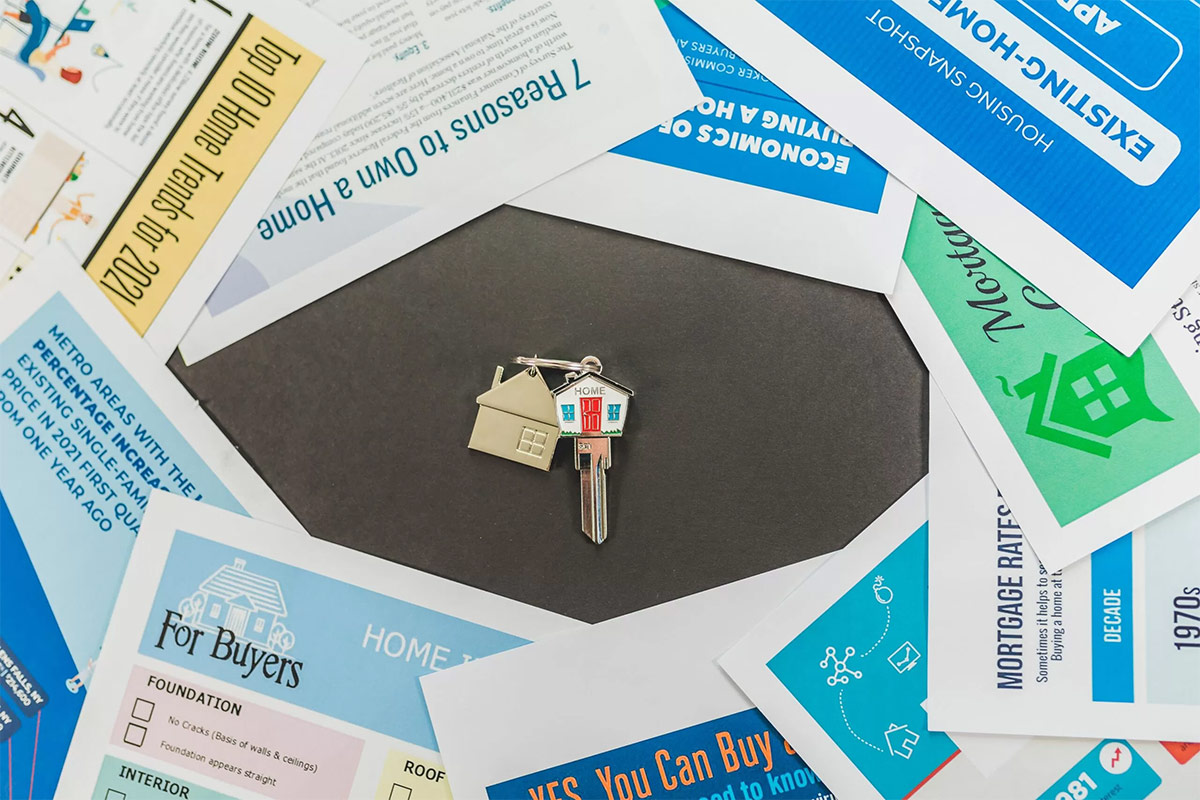 house-shaped key encircled by colorful homebuyer guides on black table