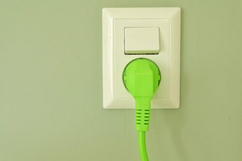 white-colored power outlet with a bright green plug mounted on green wall