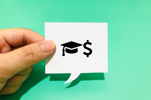 hand holding up a white thought bubble with the symbolizing student loan debt against a teal background
