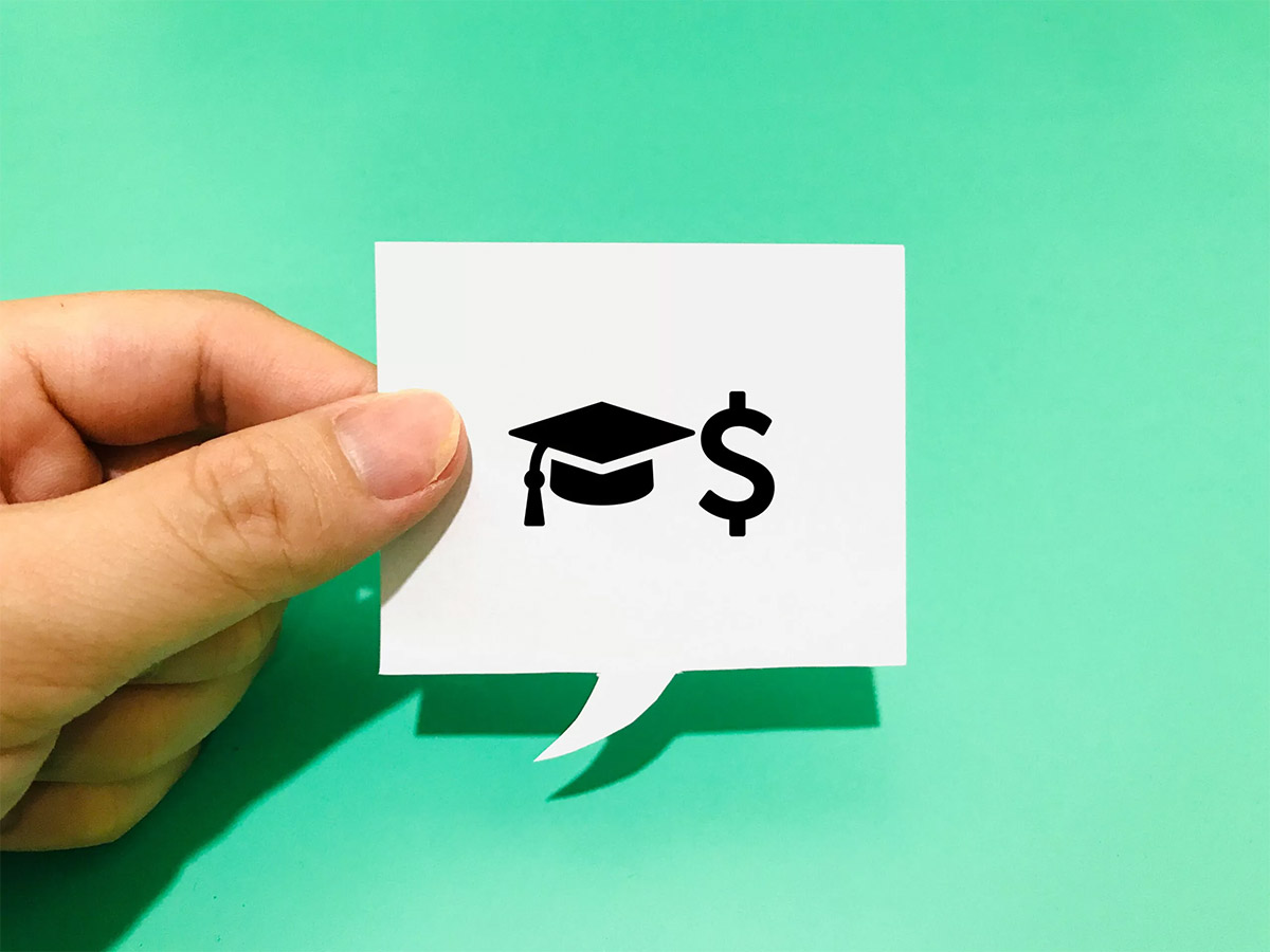 hand holding up a white thought bubble with the symbolizing student loan debt against a teal background