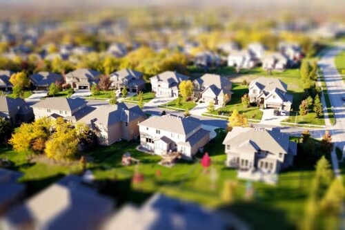 overhead shot of a suburban neighborhood with white and tan houses and green lawns