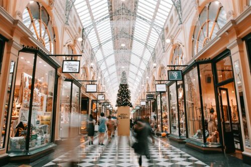 shoppers sticking to a budget while holiday shopping in a mall with a Christmas tree