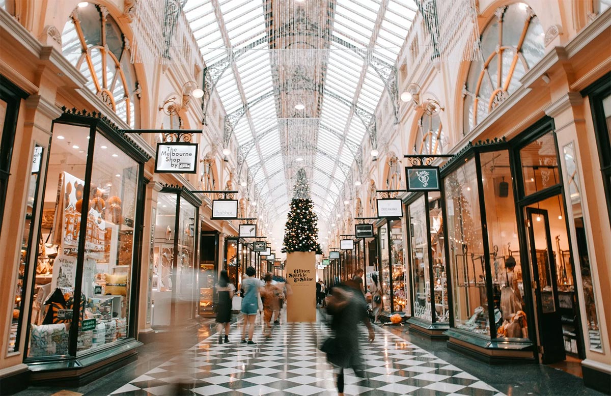 shoppers sticking to a budget while holiday shopping in a mall with a Christmas tree