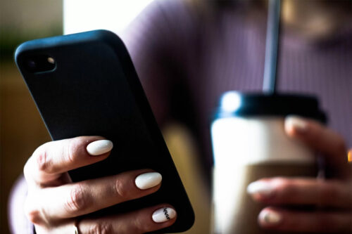 woman holding smartphone using the HRCCU Mobile Banking app to deposit a check into her account