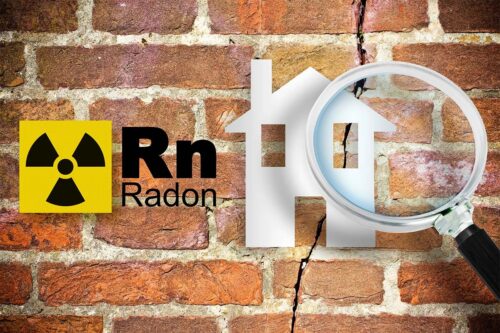 cracked, red brick wall with the radon symbol next to the image of a white house under a magnifying glass