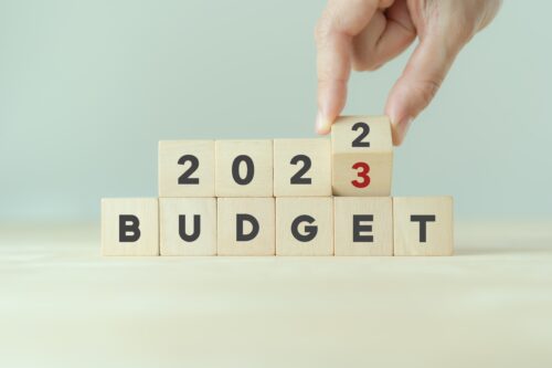 Hand flips wooden cube and changes the inscription "BUDGET 2022" to "BUDGET 2023" with grey background