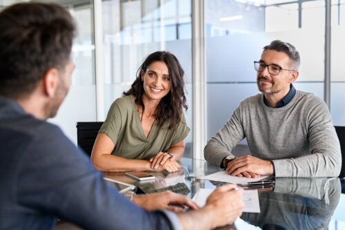 Smiling mature couple meeting with bank manager for investment. Mid adult woman with husband listening to businessman during meeting in conference room. Middle aged couple meeting loan advisor.