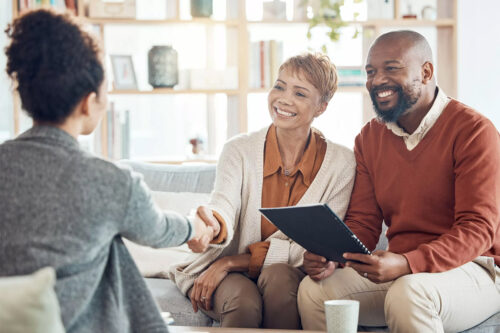 couple sits across woman shaking hands