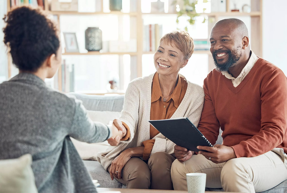 couple sits across woman shaking hands