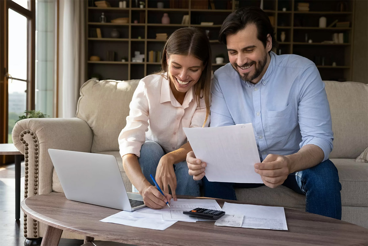 young couple sitting on couch looking at checking account