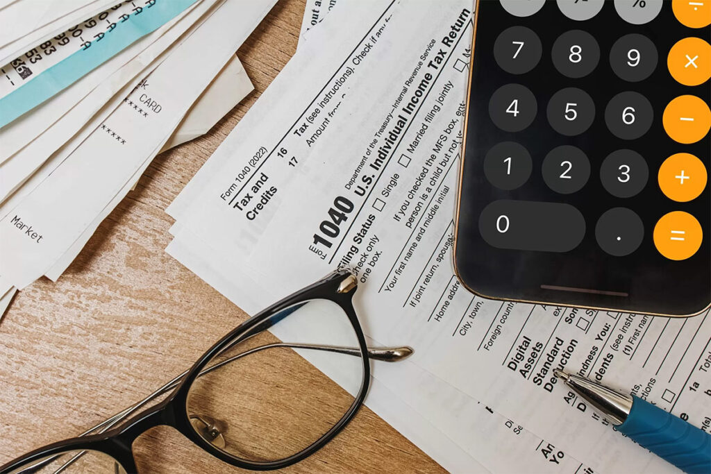 glasses, tax papers, and a calculator sit upon a desk as the tax season begins to roll around