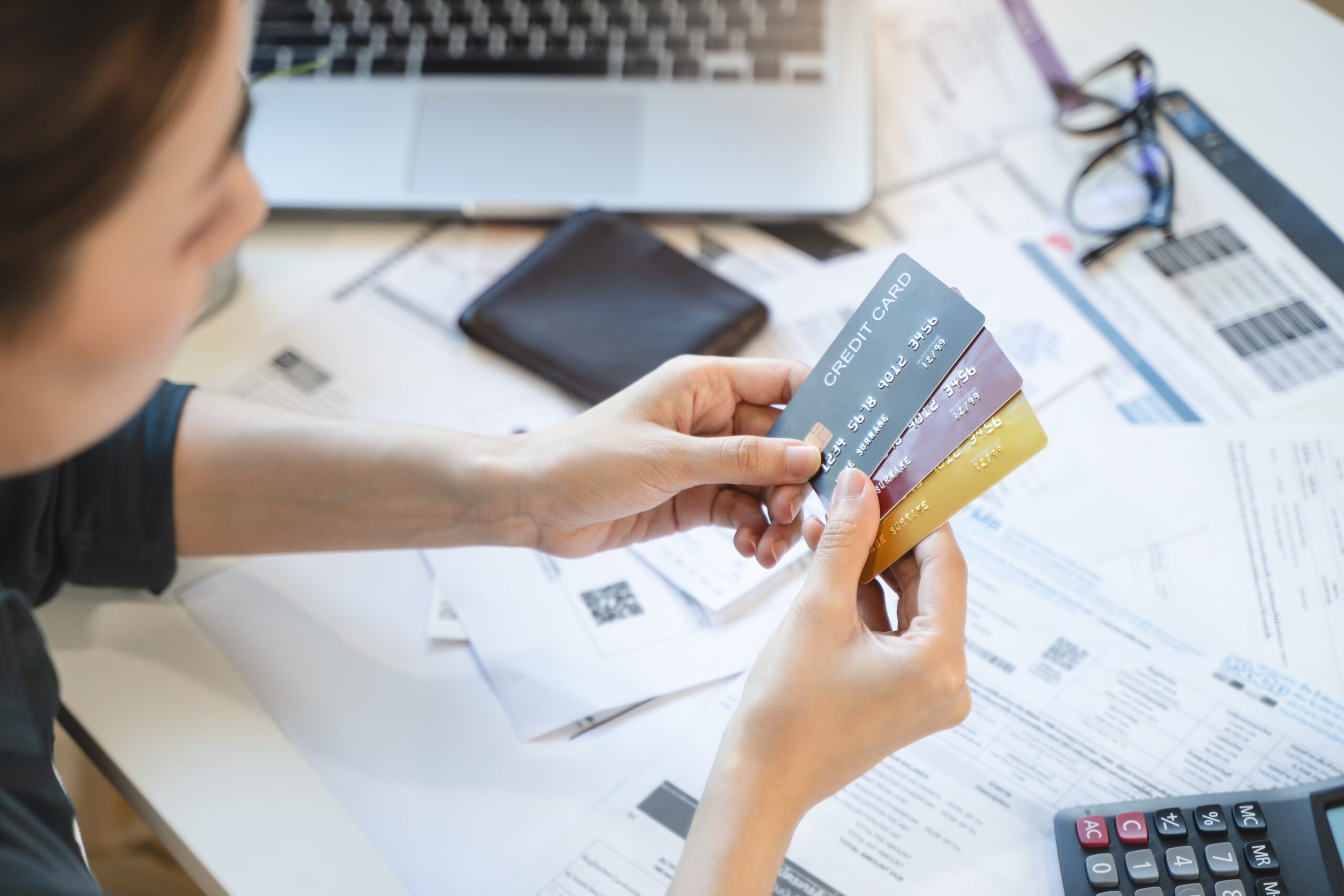 A women looks at credit cards while sitting at a desk determining her options for consolidating debt.