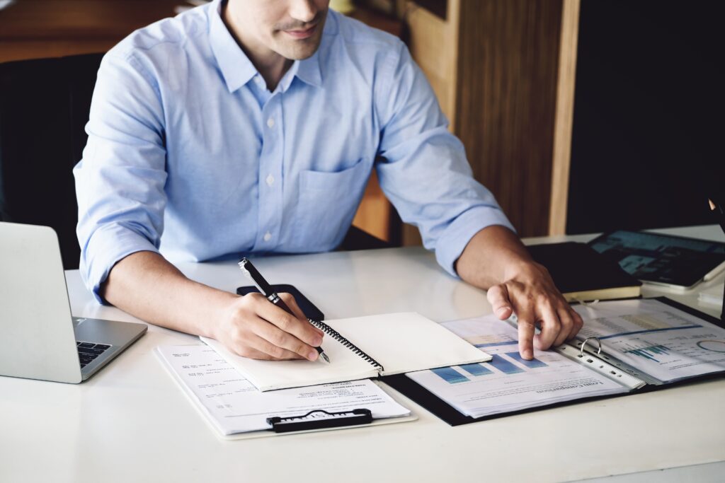 A man sits at a table with his bank statements to calculate and determine fraud risk.